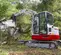 White, red and gray TAKEUCHI 12,000-14,000 lb. Mini Excavator, Reduced Tail Swing