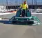 Green and black Multiquip ride-on concrete trowel with worker in the seat