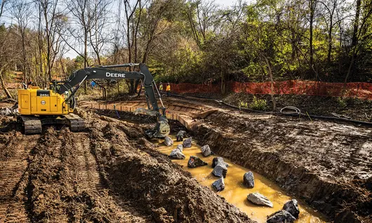 Excavatrice John Deere jaune creusant la terre