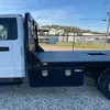 Side view of a white pickup truck with a black diamond plate flatbed and storage boxes visible beneath.