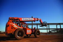Chariot élévateur JLG orange avec la marque United Rentals sur un ciel bleu